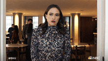 a woman is standing in a room with a nbc logo on the bottom right
