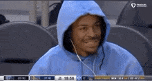 a man wearing a blue hoodie and headphones is sitting in a stadium watching a basketball game .