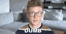 a man wearing glasses and a sweater with the word dumb written on it