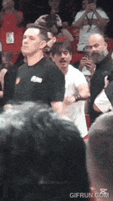 a man in a black shirt with the word eminem on it is walking through a crowd