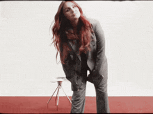 a woman in a suit stands in front of a tripod
