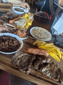 a wooden table topped with plates of food including a plate of tortillas