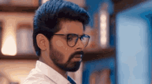 a man with glasses and a beard looks to his left