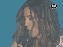 a woman singing into a microphone with a mad logo on the bottom right