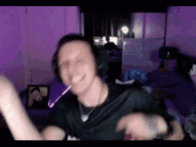 a man wearing headphones and a necklace is dancing in front of a purple background .