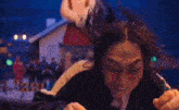 a woman is making a funny face while pointing at the camera in front of a mickey mouse statue .