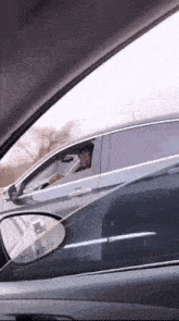 a man is driving a car and looking out the window with a reflection of him in the rear view mirror