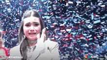 a woman is crying while confetti is falling around her and the words the voice are on the bottom