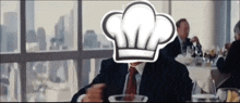 a man in a chef 's hat sits at a table