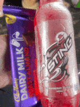 a bottle of sting strawberry flavored soda next to a cadbury dairy milk bar
