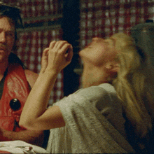 a man in a red vest is talking to a woman