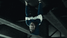 a man in a hoodie is hanging upside down from a ceiling .