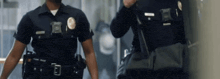 two police officers are walking down a hallway and one has a badge that has the letter e on it