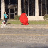 a person in a red among us costume is running down the street .