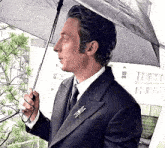 a man in a suit and tie is holding an umbrella .