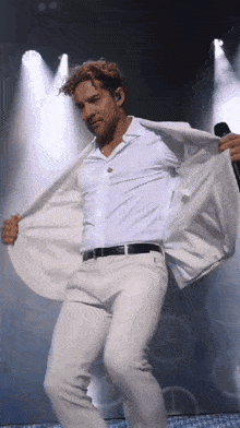 a man in a white suit is holding a microphone