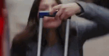 a woman is taking a picture of herself with a cell phone while holding a suitcase .
