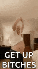a man with a very large belly is dancing in a living room with the words `` get up bitches '' .