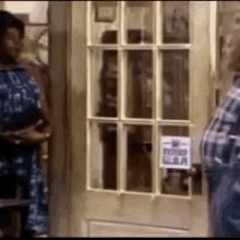 a man and a woman are standing in front of a door with a sign on it .