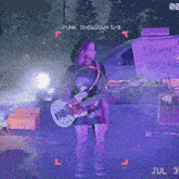 a woman playing a guitar in front of a sign that says punk showdown