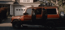 a red suv with the doors open is parked in front of a house