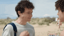 a man with a backpack is talking to another man on the beach
