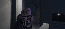 a woman with pink hair is hugging a man in front of a sign that says hollywood