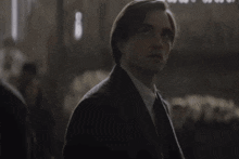 a man in a suit and tie looks at the camera in a dark room