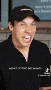 a man wearing a black hat is making a funny face and says " you 're getting decaaaf "