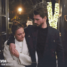 a man and woman are standing next to each other in front of a sign that says evda