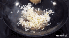 chopped onions are being cooked in a wok and the words made in animatica are visible