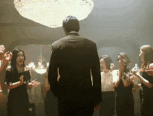a man in a suit is surrounded by women in black dresses