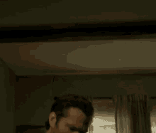 a man with a beard is standing in front of a window in a room .