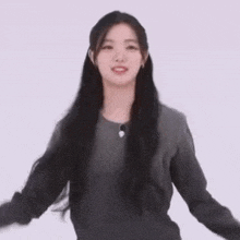 a young woman with long black hair is standing in front of a white background .