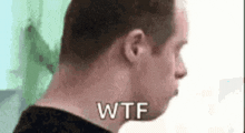 a man in a black shirt is making a funny face and says wtf .