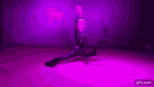 a woman in a latex suit is doing a split on a stage in front of purple lights .