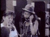 a woman in a hat is talking on a payphone