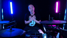 a man in a black shirt with the number 3 on it is sitting in front of a drum set