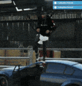 a man jumping over a fence next to a blue car