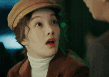 a woman wearing a hat and a turtleneck is looking at a man .