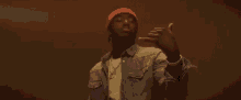 a man wearing a red beanie and a gold chain is dancing .