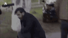 a man is kneeling down in front of a man holding a gun in a blurry photo .