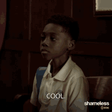 a young boy sitting in a chair with the word cool written on his shirt