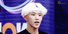 a young man with white hair and a headband on his head is making a funny face .