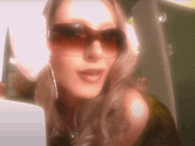 a woman wearing sunglasses looks at the camera with a green door in the background