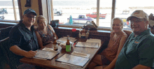 four people sit at a table with a bottle of budweiser in front of them