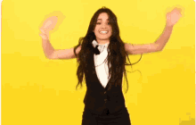 a woman wearing a tuxedo and bow tie is dancing on a yellow background .