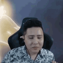 a man is sitting in a chair wearing headphones and a shirt with a floral print .