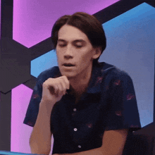 a man in a blue shirt is sitting in front of a purple and blue light .