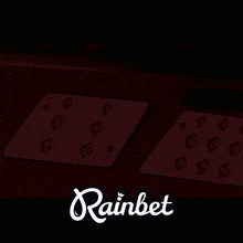 two playing cards on a table with the word rainbet in the corner